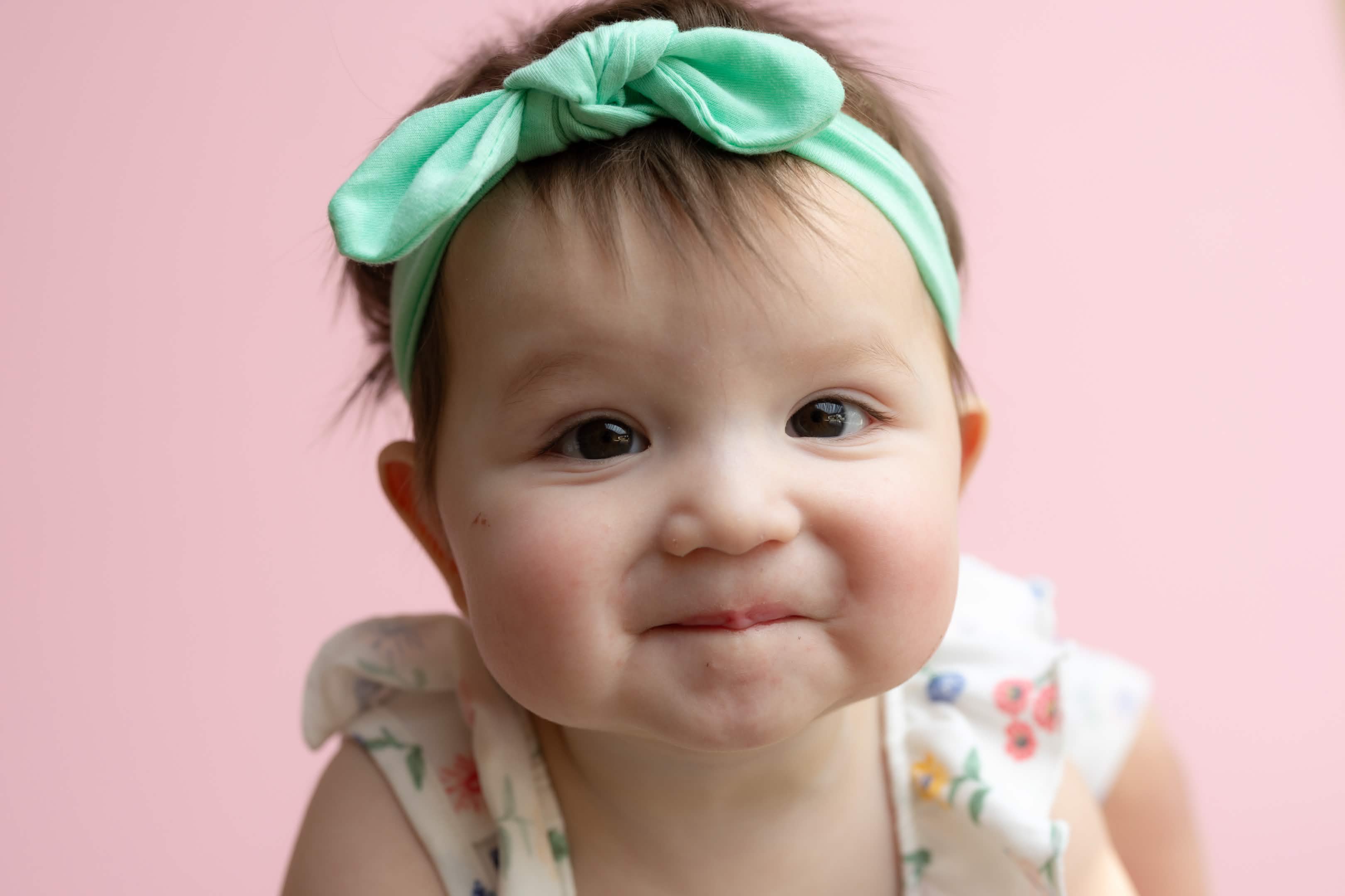 Baby portrait with mint bow on pink background